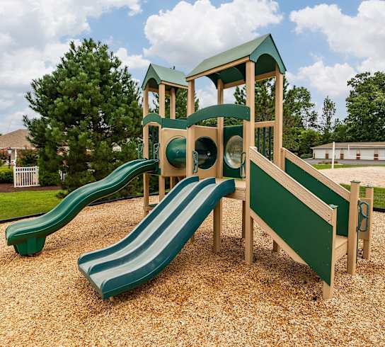 A playground with a green slide and a wooden structure.