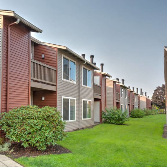 a row of townhomes with green grass and a sidewalk