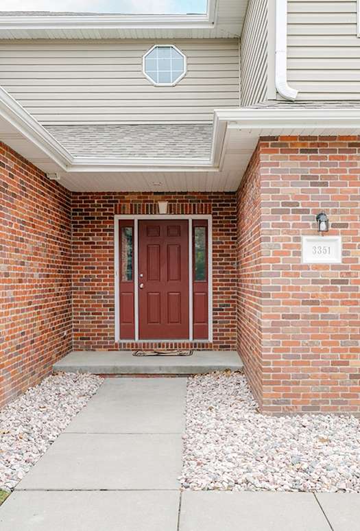 A red door is on the left side of a white garage door.