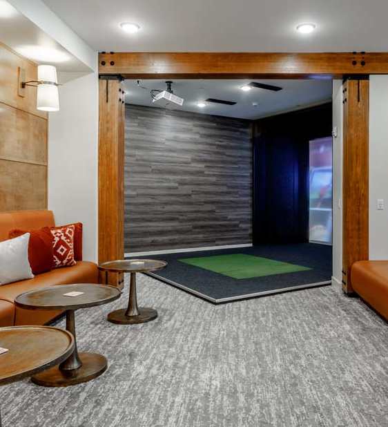 A room with a carpeted floor, a couch, and a table.