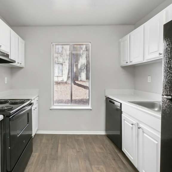 A kitchen with black appliances and white cabinets in C2b floor plan at Riverwood Crossing apartments in Roswell, GA.