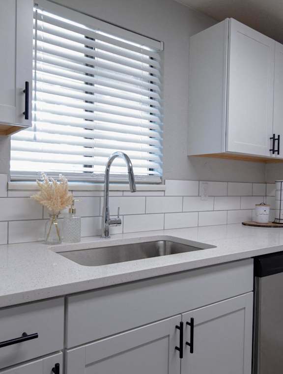 A kitchen with white cabinets and a stainless steel dishwasher.