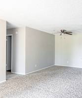 A spacious living room with a ceiling fan and a small kitchenette.