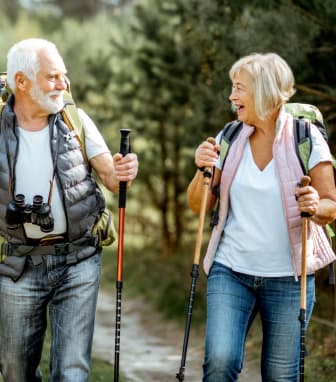 an older couple walking down a trail with trekking poles