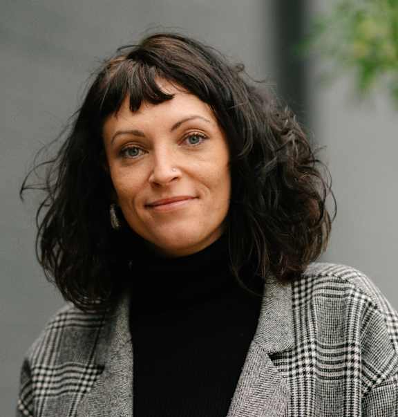 A woman with a black turtleneck and a plaid jacket.
