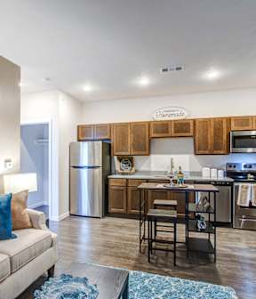 A living room with a couch and a kitchen area in the background.