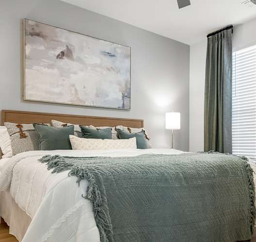 A bedroom with a large bed and a painting on the wall.
