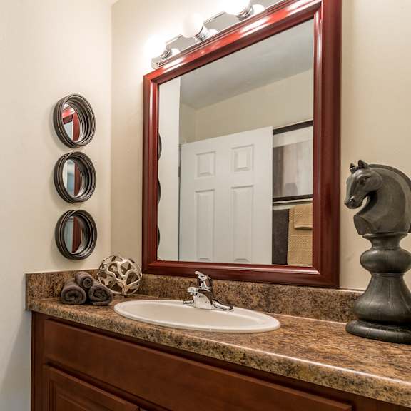 A bathroom with a brown wooden vanity and a mirror above it.