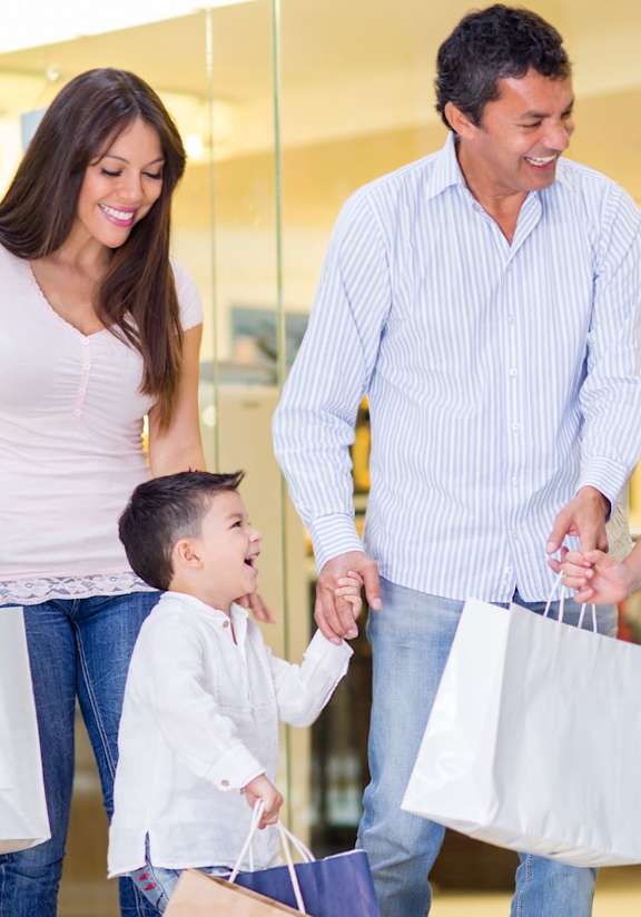A family of four with shopping bags in a mall.