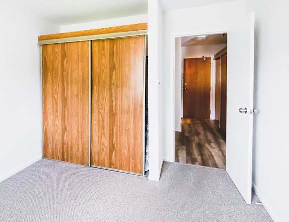 A modern kitchen with a stainless steel refrigerator and wooden flooring.