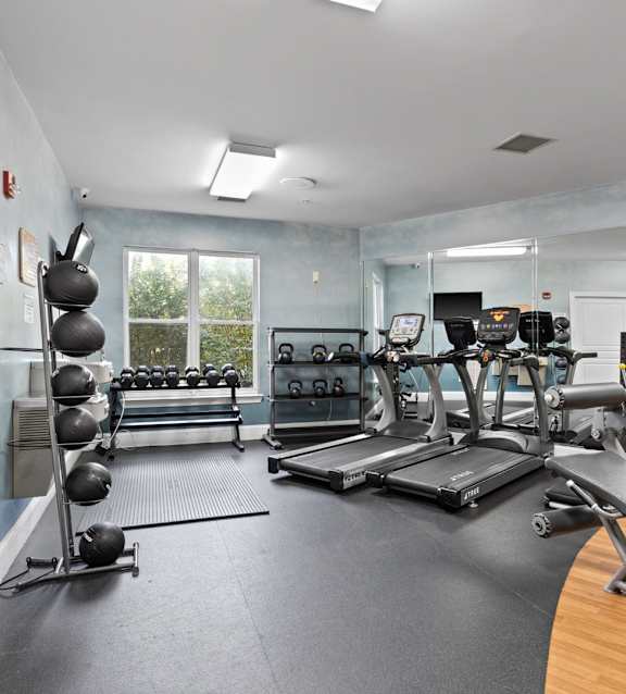 A gym with a variety of equipment including treadmills, weights, and exercise machines.