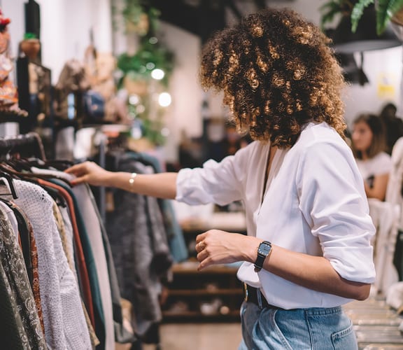 a woman looking at clothes on a rack in a clothing store