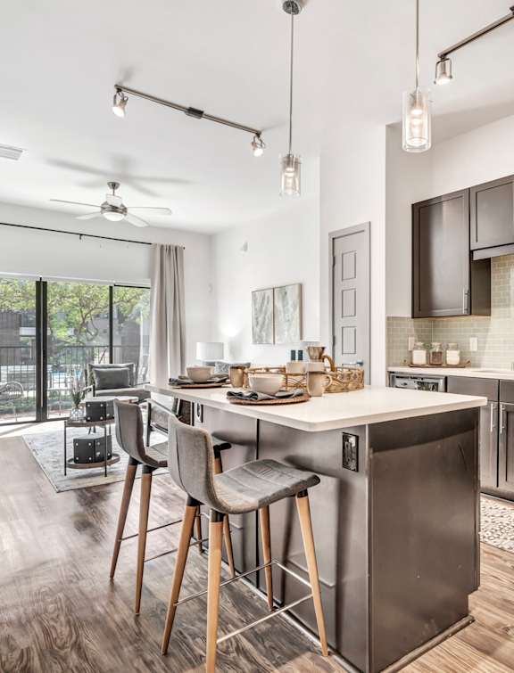 a kitchen with an island and stools in front of a sliding glass door