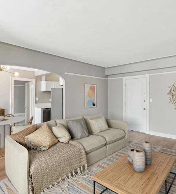 A living room with a couch, coffee table, and a dining table.