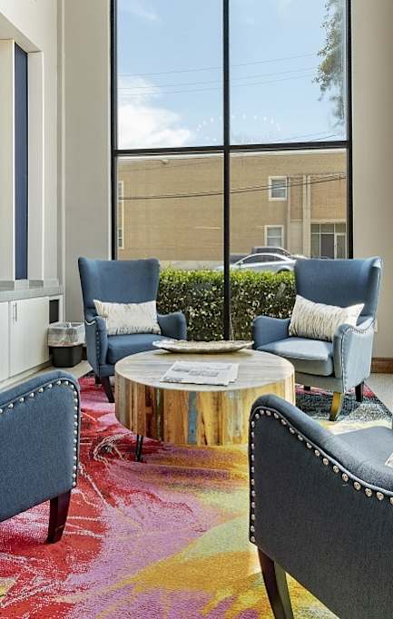 A blue chair with studded arms sits in a room with a large window.
