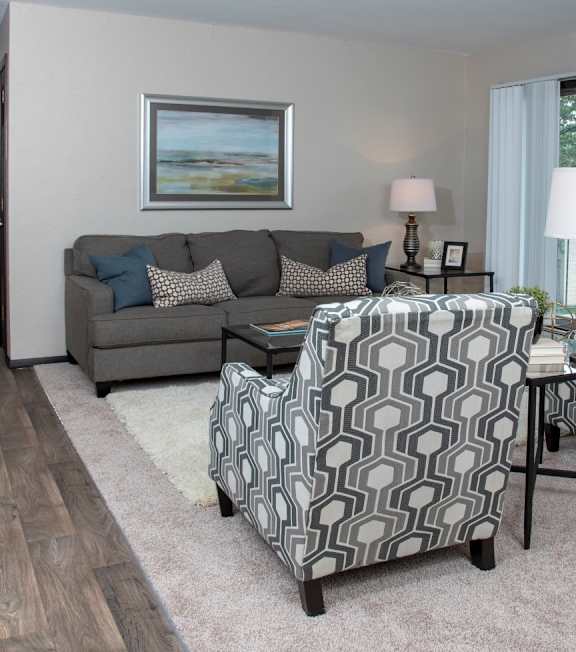 carpeted living room with a sofa and two chairs facing each other with framed art on the wall