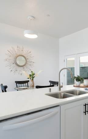 A white kitchen with a large island and a sink.