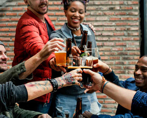 A group of people toasting with beer glasses at a table.