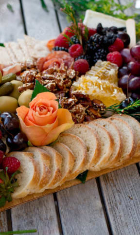 a large wooden platter with a variety of fruit and crackers on it