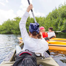 A person wearing a white shirt and a blue headband is paddling a boat.