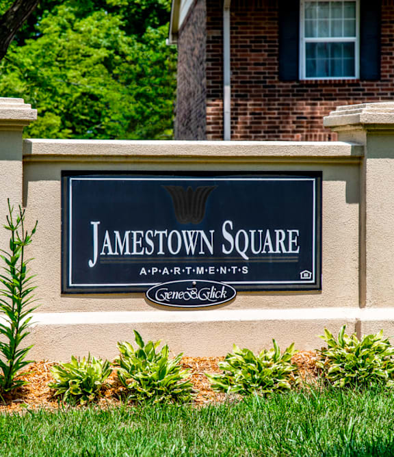 A sign that says Jamestown Square in front of a brick building.