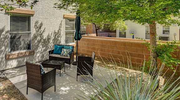 A patio with a table and chairs is surrounded by trees.