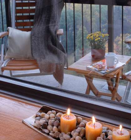 A tray with three lit candles and pebbles on a table.