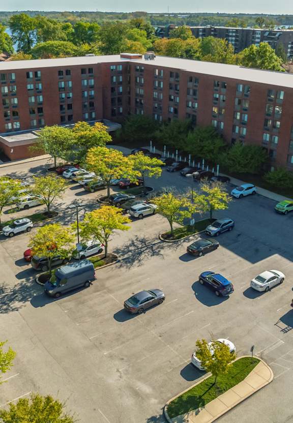 A parking lot in front of a large building with cars parked.