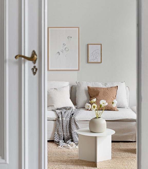 A white door opens to a living room with a couch and a coffee table.