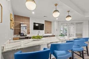 a kitchen with a long counter and blue chairs