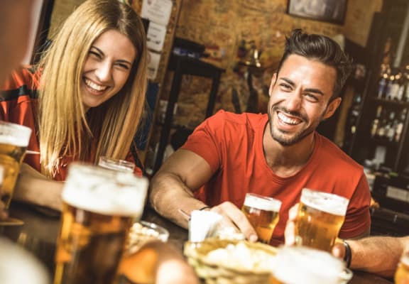 Friends at Bar Laughing and Smiling with Beers on Table 