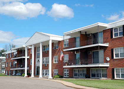 A large red brick building with a white roof and a balcony at Point of America Apartments,Minnesota