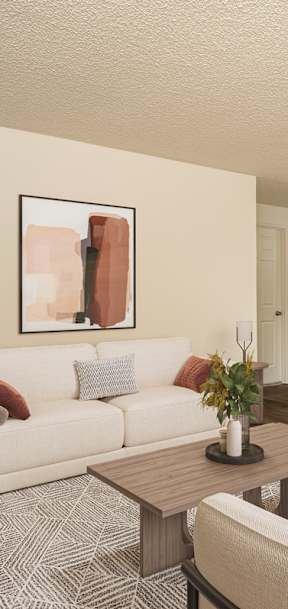 A living room with a white couch, a coffee table, and a television.