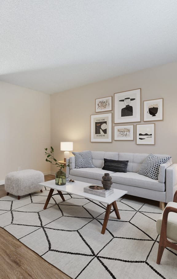 Living room with two tone paint,  Hardwood Inspired Floor, Gray/White area rug, darker gray Sofa, with artwork on wall and sliding glass door to patio. at Silverstone Apartments, California, 95618
