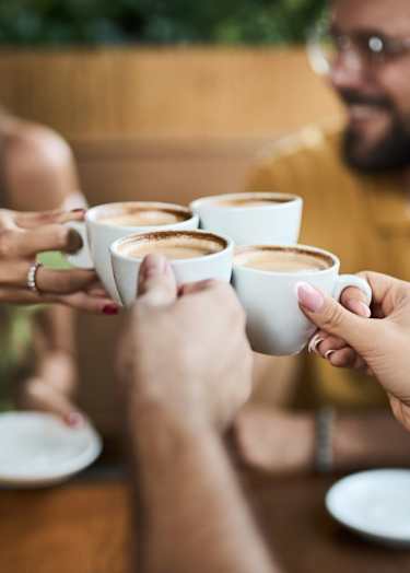 A group of people toasting with cups of coffee.