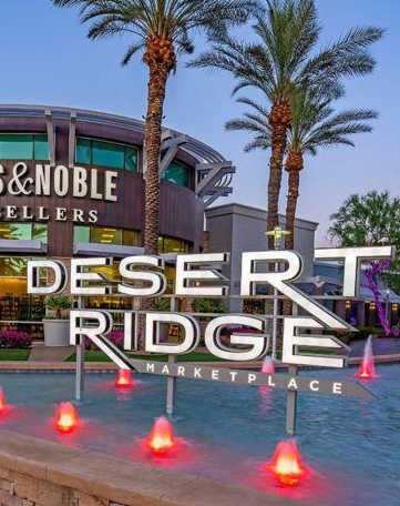 a sign for the desert ridge marketplace at night with candles in a pool
