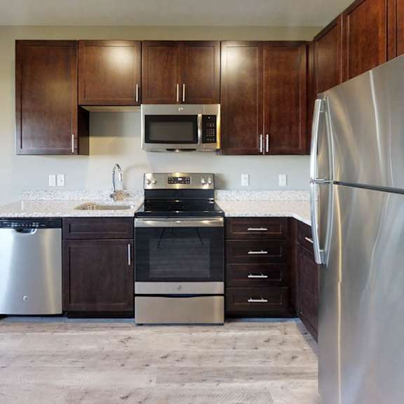 a kitchen with dark wooden cabinets, granite countertops, and stainless steel appliances
