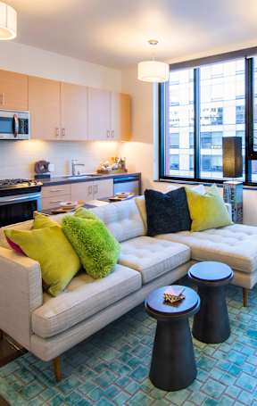 A modern kitchen with a white couch and a blue rug.