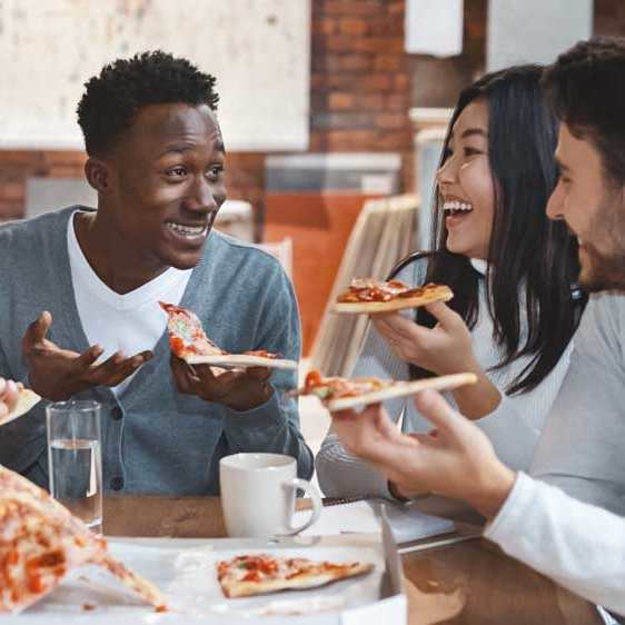 A group of people enjoying pizza together at a table.