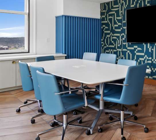 A conference room with a white table and blue chairs.