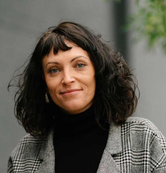 A woman with a black turtleneck and a plaid jacket.