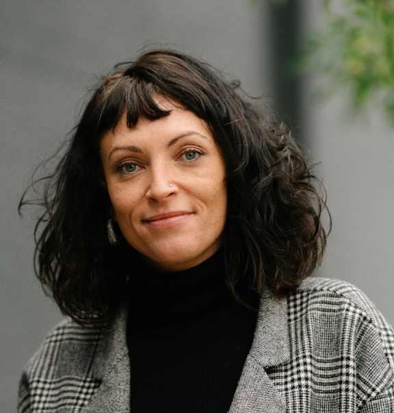 A woman with a black turtleneck and a plaid jacket.