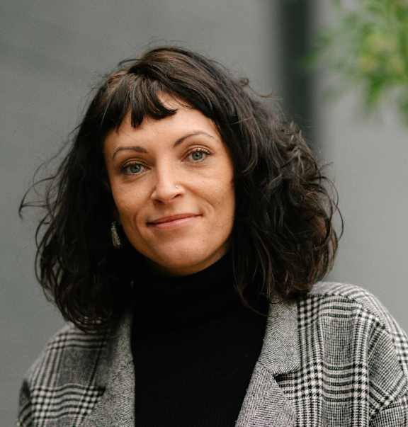 A woman with a black turtleneck and a plaid jacket.