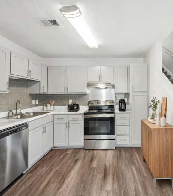 A modern kitchen with stainless steel appliances and wooden floors.