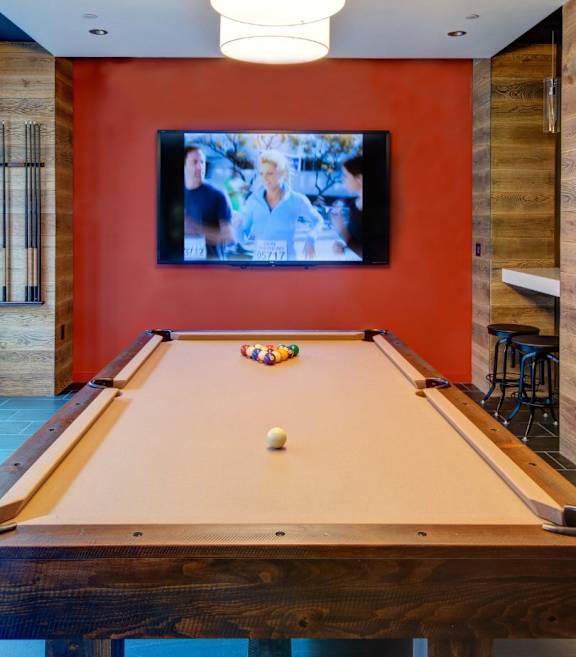 A pool table with a television on the wall.