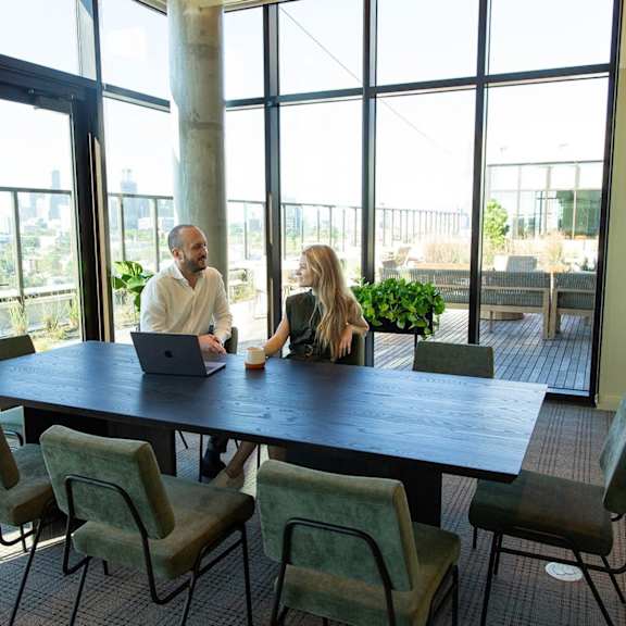 Two people sitting at a table in a room with large windows. at Scout Living, powered by Placemakr Apartments, Atlanta, GA, 30308