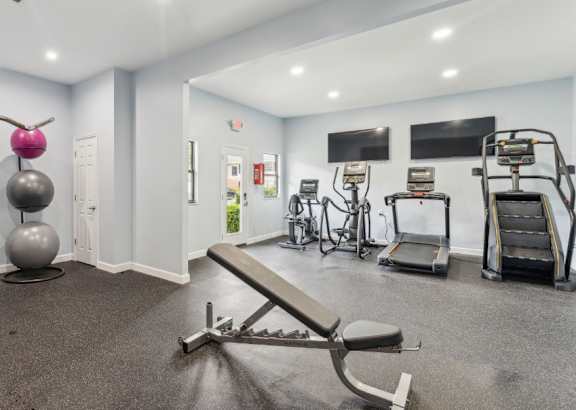 A gym with a variety of equipment including a squat rack, a bench, and a treadmill.