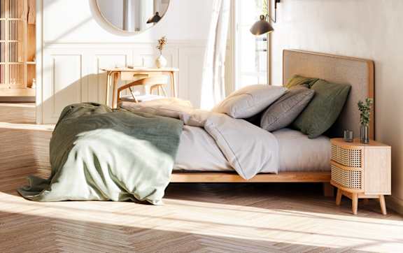 A well-lit bedroom with a bed, a chair, a potted plant, and a fireplace.