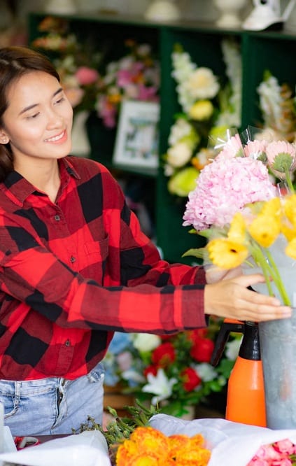 a woman standing in a flower shop with a laptop computer  at The Meadows, Georgia, 31302