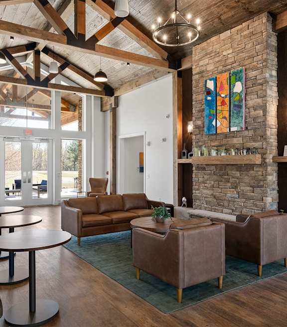 A living room with a stone fireplace and a large window.